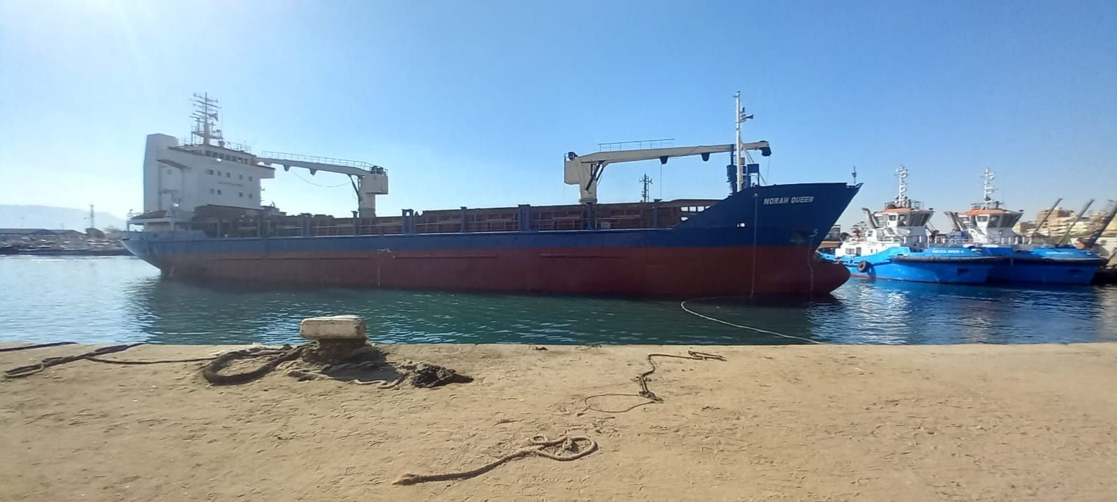 MV Norah Queen at berth in daylight with tugs alongside